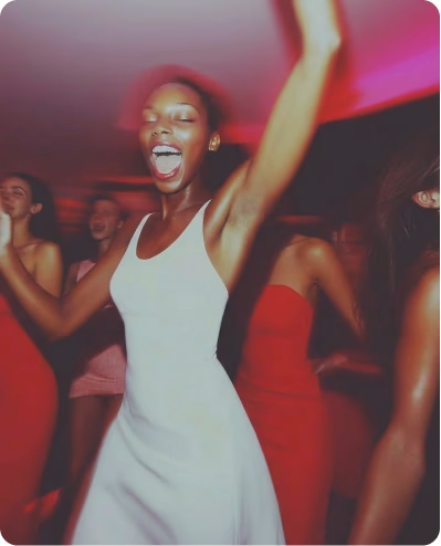 Groupe de femmes dansant dans une ambiance lumineuse rouge, une femme en robe blanche au premier plan